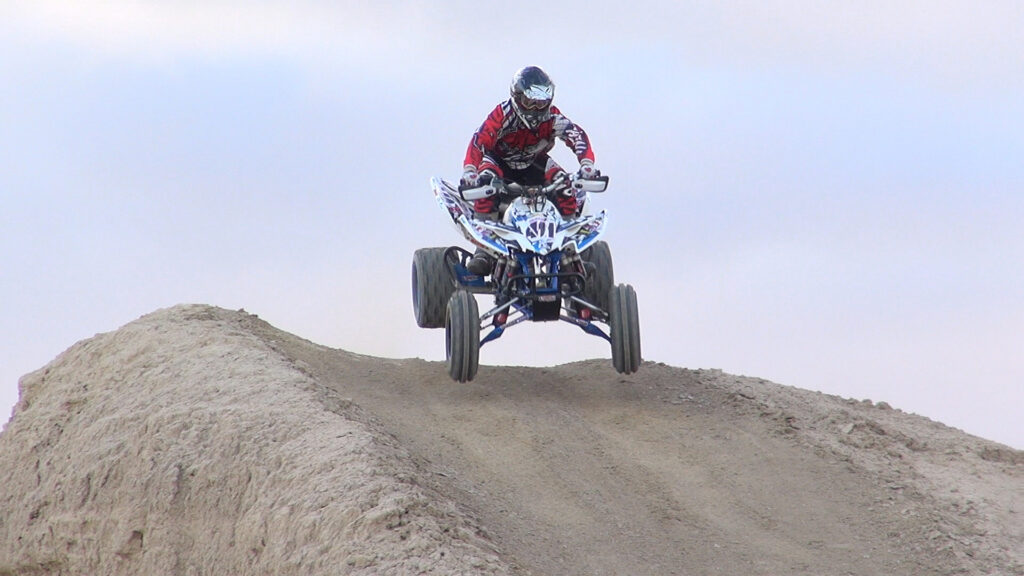Honda 400EX catching air over a sandy hill during Elka Stage 5 shock testing.