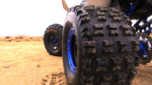 Low right-rear view showing Maxxis RAZR tires and tire blocks.