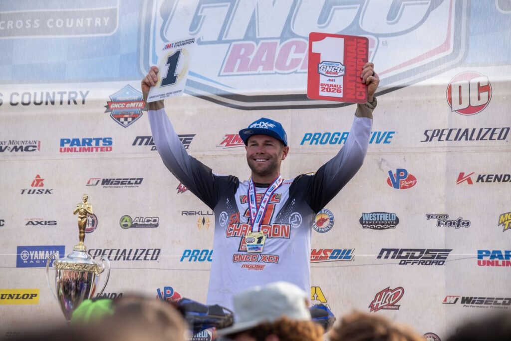 Brycen Neal raises his championship plates on the podium at the 2026 Ironman GNCC