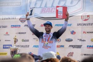 Brycen Neal raises his championship plates on the podium at the 2026 Ironman GNCC