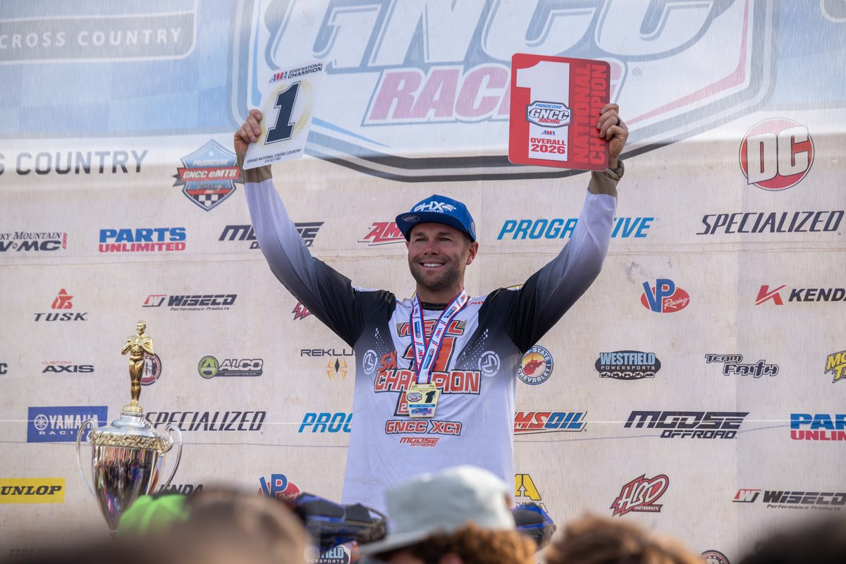 Brycen Neal raises his championship plates on the podium at the 2026 Ironman GNCC