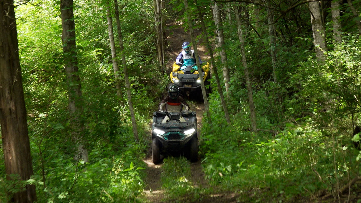 Kawasaki Brute Force 750 leading a Can-Am Outlander 700 downhill toward the camera during a braking test.
