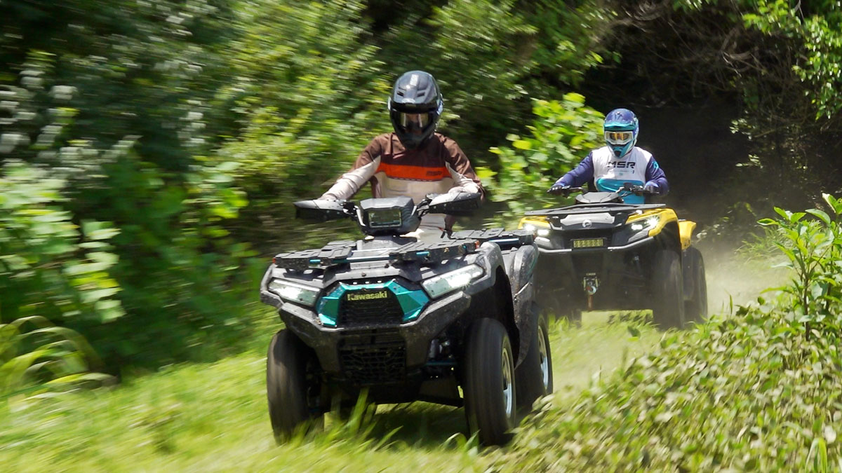 Kawasaki Brute Force 750 leads a Can-Am Outlander 700 across a grassy field, heading back toward the camera.