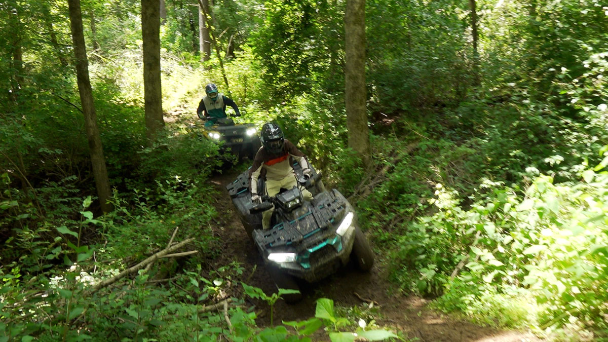 Kawasaki Brute Force 750 leading a Can-Am Outlander 700 down a trail, dropping into a ditch.