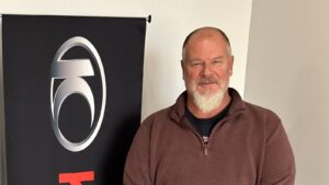 Joe Wofford beside the KYMCO emblem