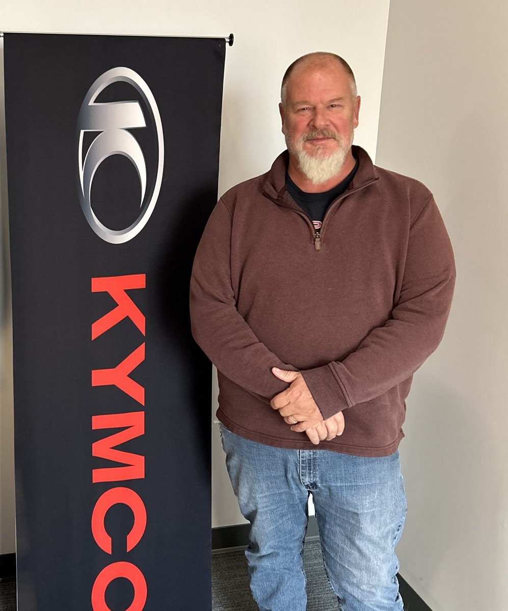 Joe Wofford standing beside a KYMCO banner